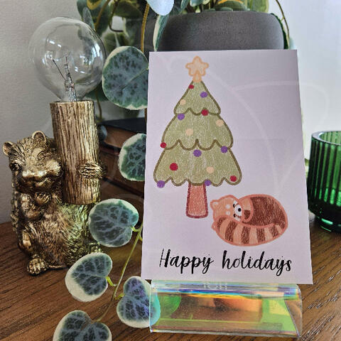 Red panda laying under christmas tree Card